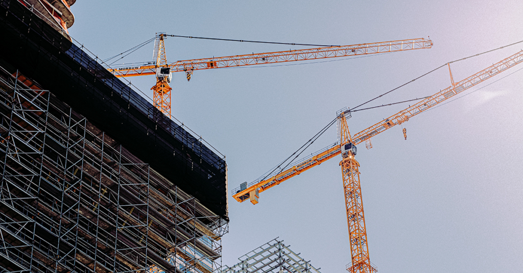 Two orange cranes above a construction building project