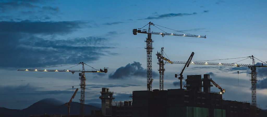 Cranes over a Construction Site at Dusk - TrebleHook Construction CRM - AEC firms